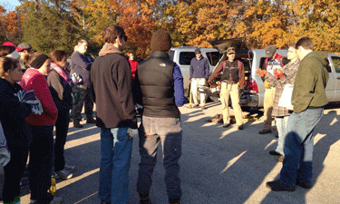 Jill Erickson (far right, wearing orange gloves) explains to volunteers how and why nonprofit conservation group Kansas City WildLands removes invasive bush honeysuckle on park land. 